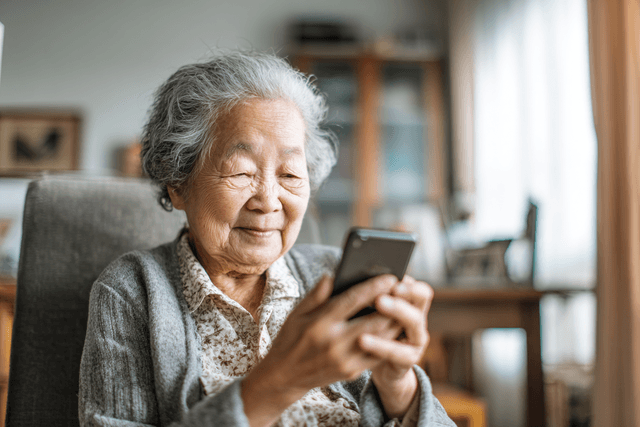 A grandmother smiling while reading a message on her phone