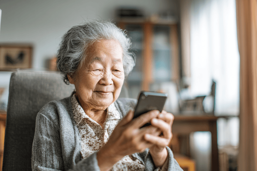 A grandmother smiling while reading a message on her phone