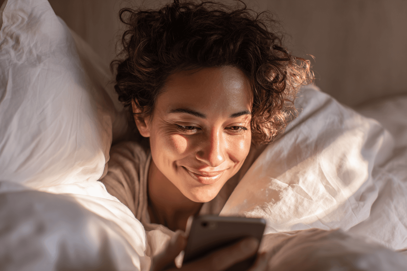 A young woman reading a meaningful message on her phone in the soft morning light